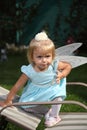 Sweet smiling little girl with long blond hair, sitting on grass in summer park, closeup outdoor portrait. Royalty Free Stock Photo